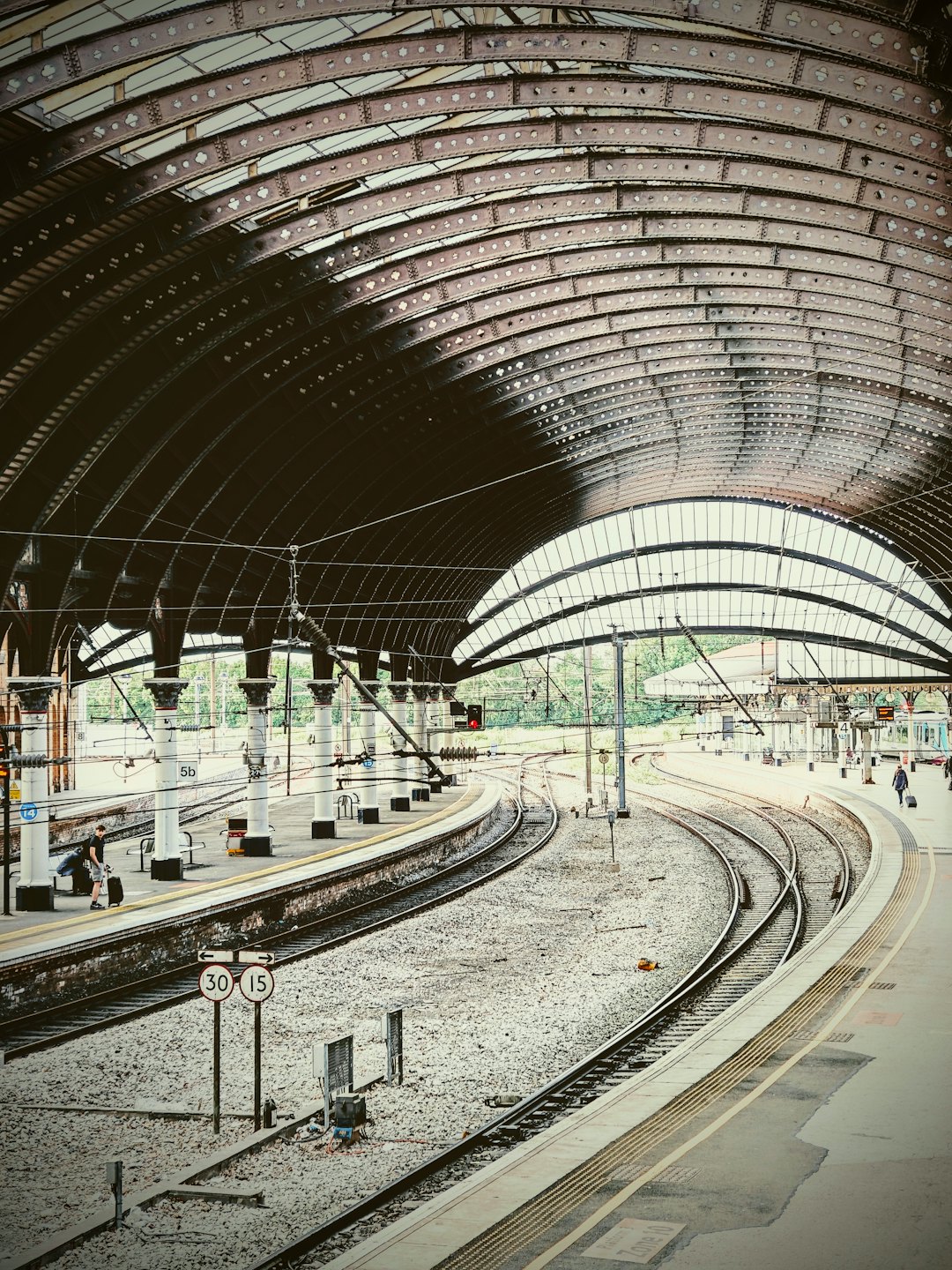 Pendolari camminano sulle banchine all'interno di una storica stazione ferroviaria ad arco.