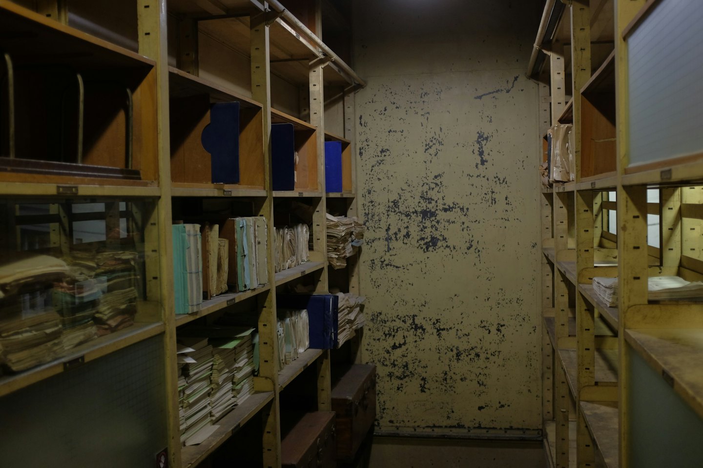 Scaffali di metallo pieni di vecchi documenti in uno stretto archivio.